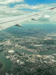 Aerial view of London. View of the city centre of London from the window of the plane. Flying over the city with blue and grey landscapes. View of the river and skyscrapers.