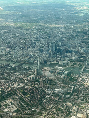 Aerial view of London. View of the city centre of London from the window of the plane. Flying over the city with blue and grey landscapes. View of the river and skyscrapers.