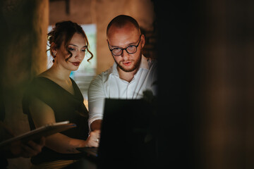 Business colleagues engaged in discussion and data analysis on a laptop during a strategic meeting indoors.