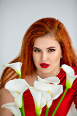 Close-up of a red-haired woman in a red dress holding a bouquet of calla lilies