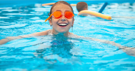 Young beautiful happy girl swimming in swimming pool. Horizontal image.