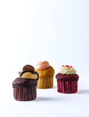 Neat, small cupcakes decorated with sweets and cream on a white background.