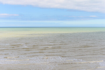 The North Sea with different shades of brown, yellow, green and blue on a clouded summer day at the Opal Coast in Ault, France
