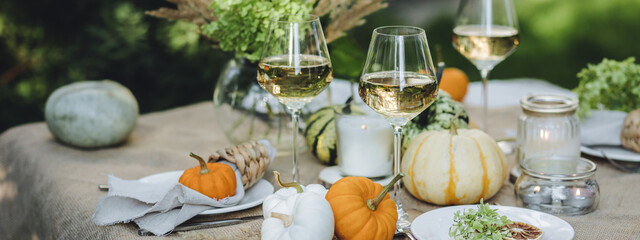 Banner. Cozy fall table decoration for Thanksgiving family dinner, romantic autumn wedding outdoors with small pumpkins, candles. White wine. Countryside style, cottage core, beautiful elegant setting
