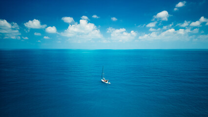 A sailboat in blue turquoise seawater near Phuket island in summer season during travel holidays vacation trip. Andaman ocean, Thailand. Tourist attraction with blue cloud sky.