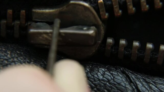 Close-up unzipping vintage zipper metal zipper on a leather jacket. it is unbuttoned. the zipper slowly unzips
