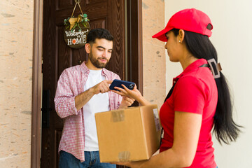 Delivery woman handing package to customer and asking for digital signature on a phone at house...