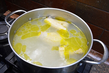 preparing delicious chicken broth in a silver pan in the home kitchen. an ingredient for further preparation of soup. light rich broth is good for the diet