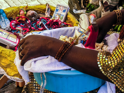 Mother of Candomble saint holds a basket with popcorn and the image of Saint George (Ogum) in front of the Church