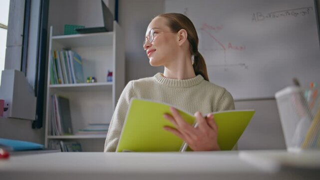 Lady teacher looking window at workplace closeup. Happy tutor checking homework