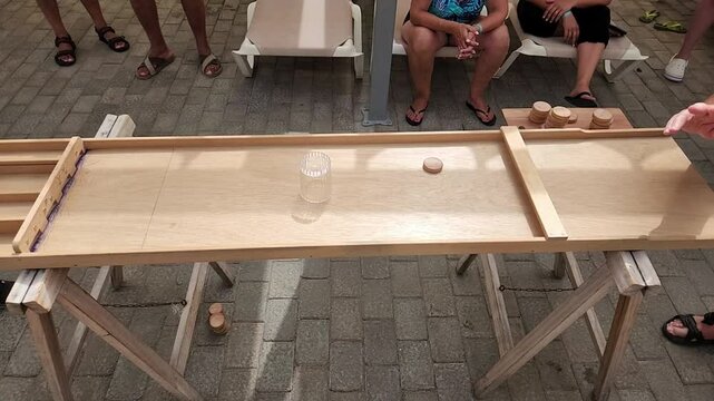 Close-up view of people playing Carrom game with wooden discs in hotel during vacation. Spain.