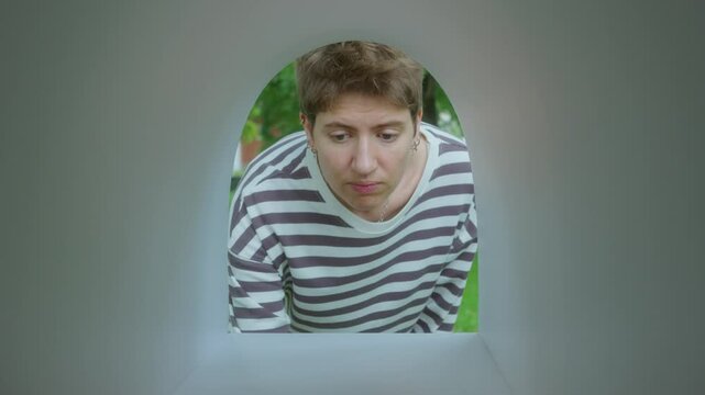 Young woman opening empty mailbox, checking it and getting disappointed about not getting correspondence she was expecting. View from inside of mailbox