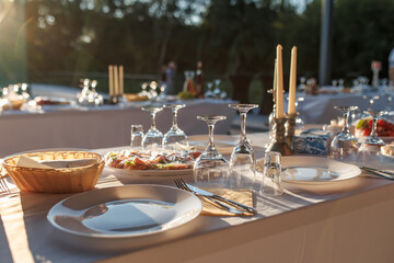 empty wine glasses on banquet served table in open air in rays of setting sun