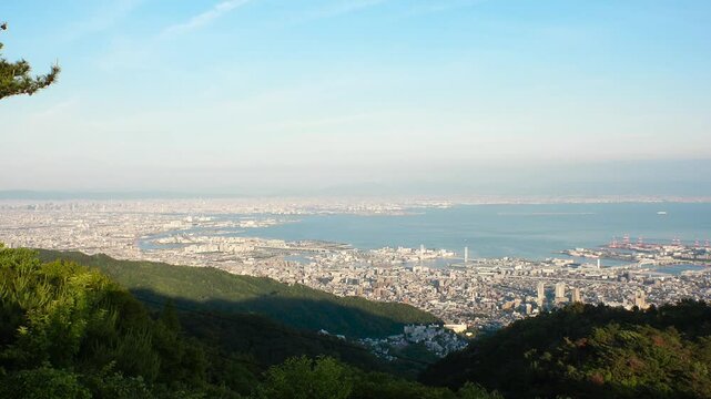 KOBE, HYOGO, JAPAN - JUNE 2024 : Aerial high angle panoramic view around Kobe city, Kobe port, Osaka city and Osaka bay in daytime. View from top of Rokkosan (Mt. Rokko).