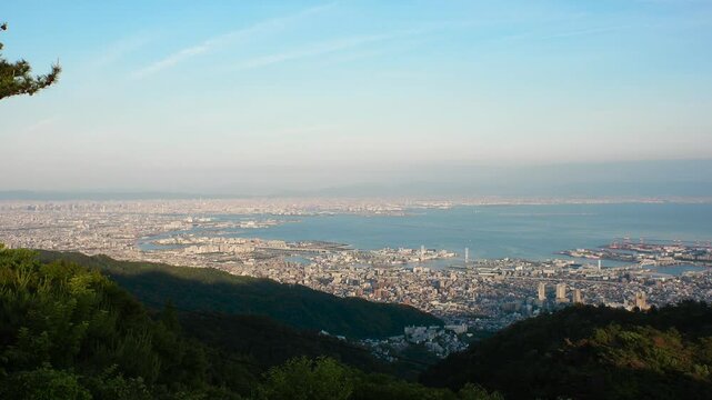 KOBE, HYOGO, JAPAN - JUNE 2024 : Aerial high angle panoramic view around Kobe city, Kobe port, Osaka city and Osaka bay in daytime. View from top of Rokkosan (Mt. Rokko).