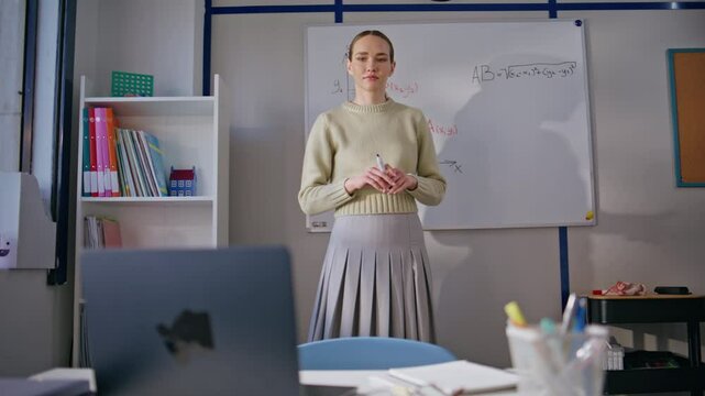 Young teacher explaining math standing whiteboard. Tutor working laptop online