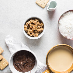 Overhead view of mise en place for making chocolate fudge with cookies and fudge pieces, Top view of ingredients of hazelnut chocolate fudge, process of making chocolate fudge