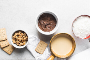 Overhead view of mise en place for making chocolate fudge with cookies and fudge pieces, Top view of ingredients of hazelnut chocolate fudge, process of making chocolate fudge