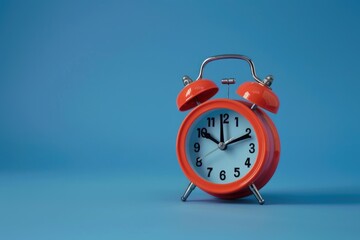A close-up shot of a red alarm clock sitting on a blue background