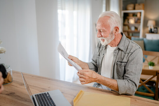 senior caucasian man open mail letter or document envelope at home