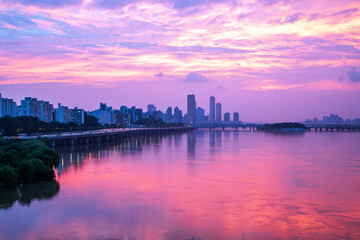 Dongjak-gu, Seoul, South Korea - July 17, 2023: Sunset view of flood of Han River with Olympic Boulevard against apartments and Yeouido high-rise buildings
