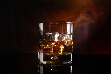 A sophisticated shot of a glass of whiskey on the rocks, showcasing the golden hues of the drink and the clarity of the ice cubes, set against a dark and warm background.