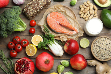 Flat lay composition with fresh fish and other products for balanced diet on wooden table