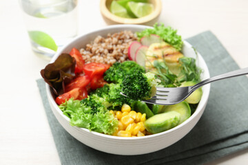 Healthy meal. Eating tasty products with fork from bowl on white table, closeup