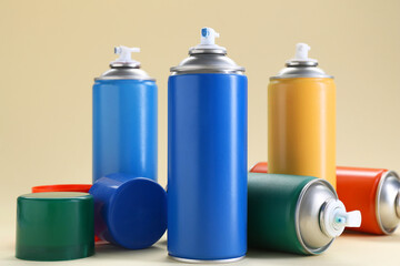 Many spray paint cans on beige background