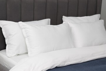 Many soft pillows on bed at home, closeup