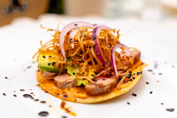 gourmet tostada with avocado, tuna, and crispy onions