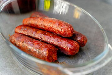 freshly cooked sausages in glass dish - grilled
