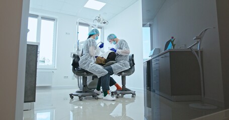 Dentist and Assistant Treating Patient in Clinic