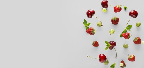 Different flying berries on grey background with space for text