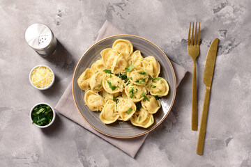 Plate of boiled dumplings with cheese and basil on grey background