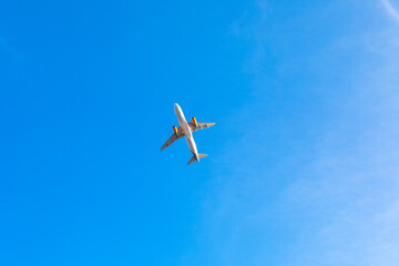 Airplane soaring through clear blue sky. White airplane is flying in the sky above a blue sky. The sky is clear and the sun is shining brightly