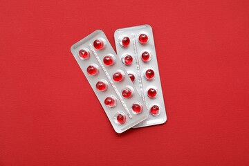 Blister pack with red pills on color background