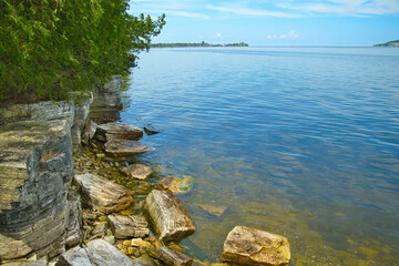 Sunny Summer landscape of a lush green forest bordering Lake Michigan beneath a bright blue sky...