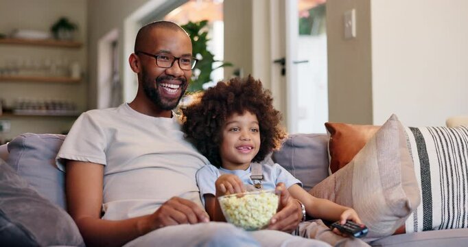 Happy father, child and watching tv with popcorn for entertainment, bonding or movie on sofa at home. Dad, kid or little boy with smile or remote for online streaming, show or cartoon in living room