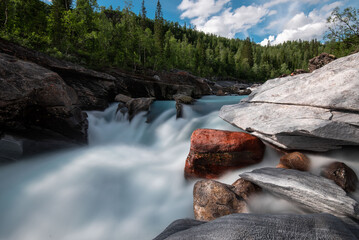 Long exposure of flowing river Marmorslottet in Rana, Helgeland, Norway. Wild stream through marble rocks turned to softness in 10 second exposure. Smooth marble rock formations with turquoise rapids