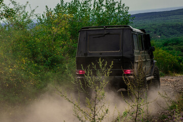 Off-road vehicle goes on mountain way. 4x4 travel trekking. Motion the wheels tires and off-road that goes in the dust on the sand. Jeep outdoors adventures. Road adventure. Adventure travel. © Volodymyr