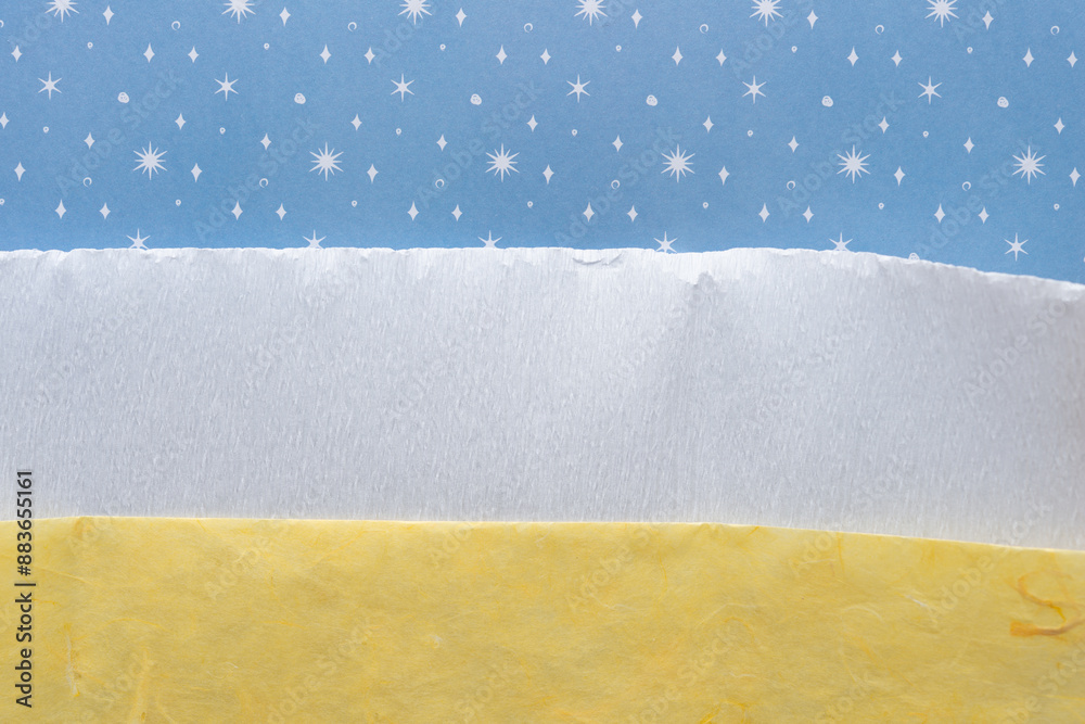 Wall mural folded, layered white crepe paper tucked between blue paper with stars or snowflakes and yellow tissue paper with texture