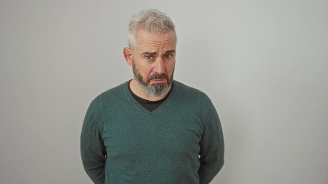 Depressed young man in a sweater standing alone, showing a sad expression. angry and afraid, he cries out in distress against a white isolated background.