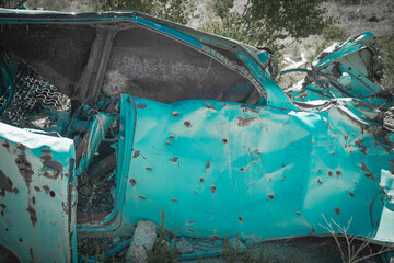 Crushed car with rusted holes abandoned in the wilderness