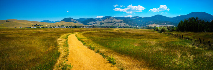 Tranquil rural dirt road curving through the prairie toward Lolo National Forest in Helena, Montana