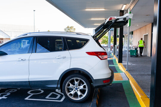 Car parked in direct to boot park at shopping centre collecting groceries with boot open