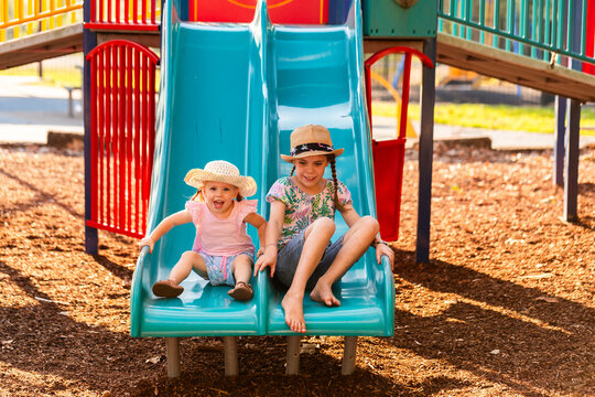 Park playground in afternoon light with kids sliding down slide