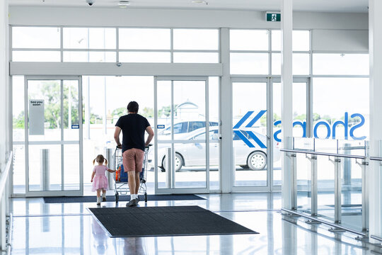 Dad with toddler and shopping trolley leaving the shops