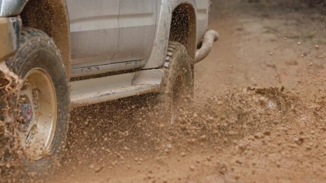 Cars running on off-road roads and splashing mud on natural paths. Off-road travel on muddy road. Offroad travel and driving concept, Wheel closeup in a countryside landscape with a muddy road.