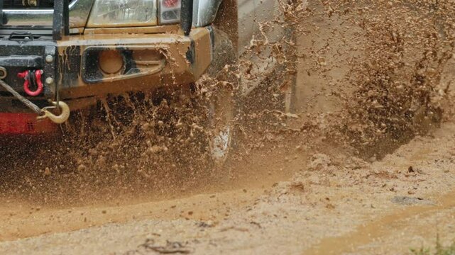 Cars running on off-road roads and splashing mud on natural paths. Off-road travel on muddy road. Offroad travel and driving concept, Wheel closeup in a countryside landscape with a muddy road.